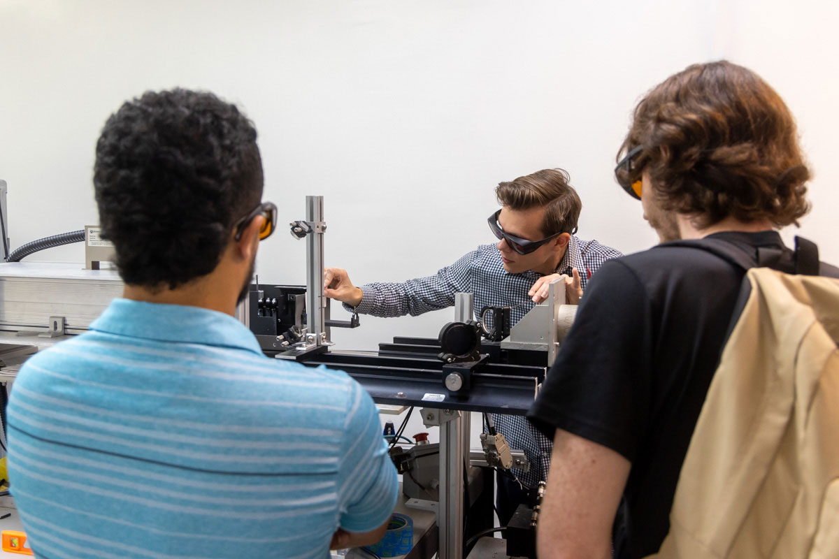 2022 UCF Senior Design students sponsored by CMS Laser gathered around UV laser workstation